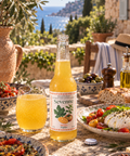 Bouteille et verre Sevenne Mangue Figuier, boisson pétillante sans alcool, sur une table de terrasse méditerranéenne